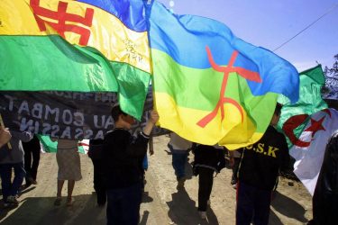 Demonstrators wave Berber flags 18 April 2002 during a march by Berbers in Agouni Arouss. Algeria's ethnic Berbers erected a stele in commemoration of Massinissa Guermah, a young man whose death in police custody a year ago sparked an uprising dubbed the Black Spring. Marches were held in other Kabylie villages in homage to Guermah. AFP PHOTO HOCINE (Photo by HOCINE ZAOURAR and - / AFP)